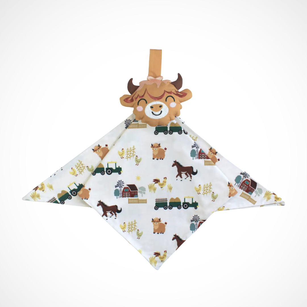 Baby comfort blanket with farmyard inspired print and a plush highland cow toy on a white background