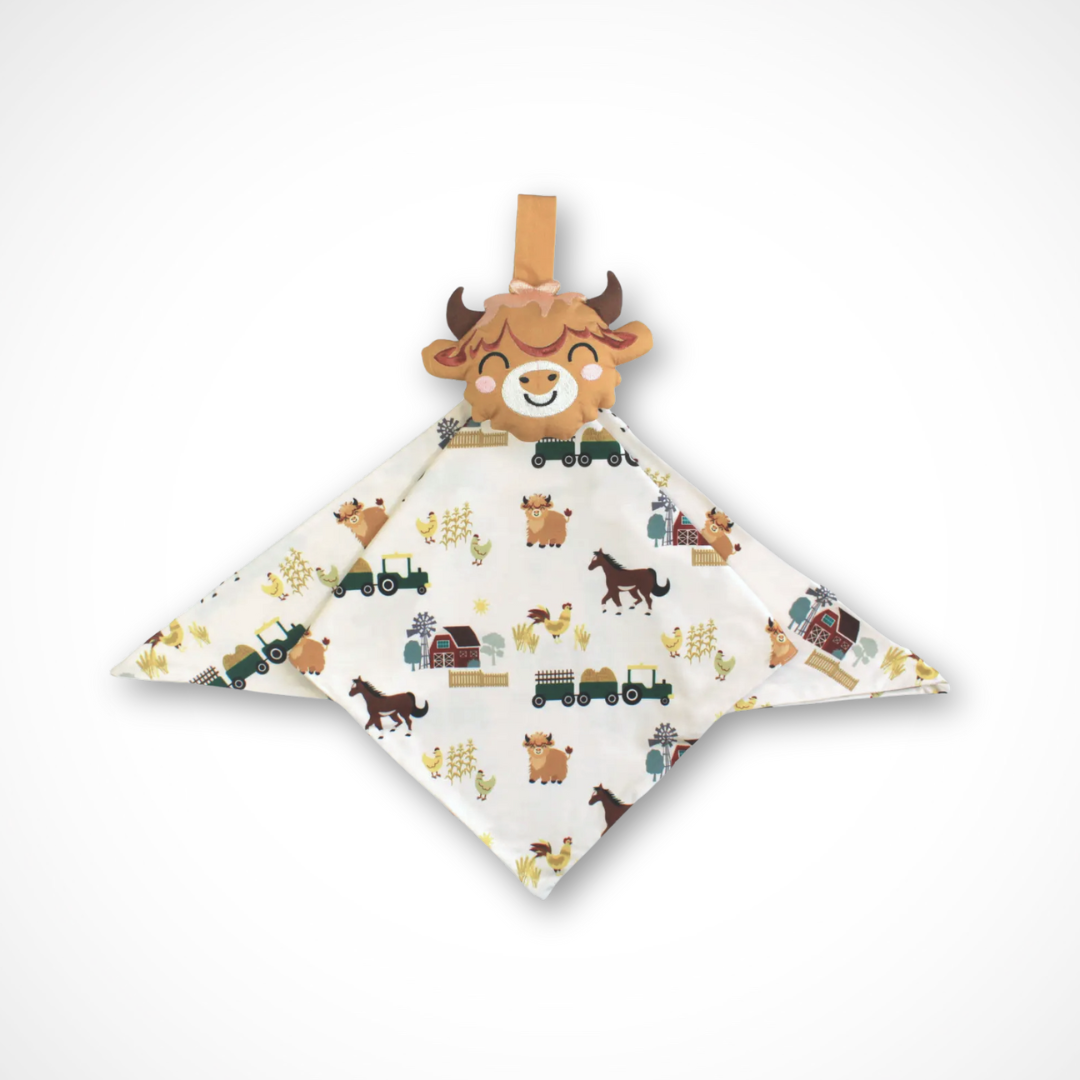 Baby comfort blanket with farmyard inspired print and a plush highland cow toy on a white background
